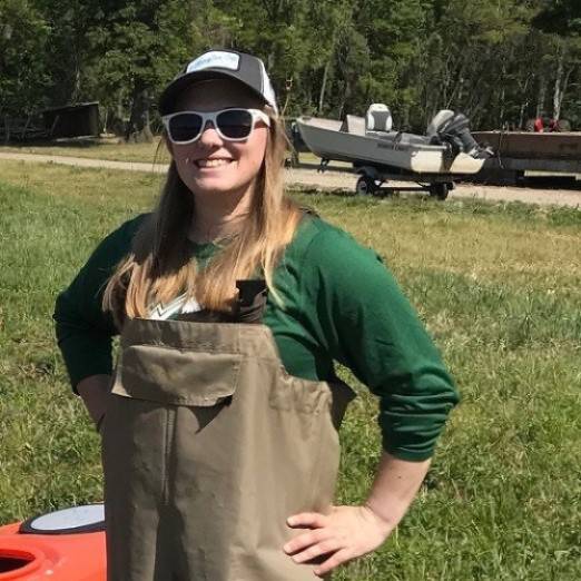 Katie poses for the camera with a small boat in the background.